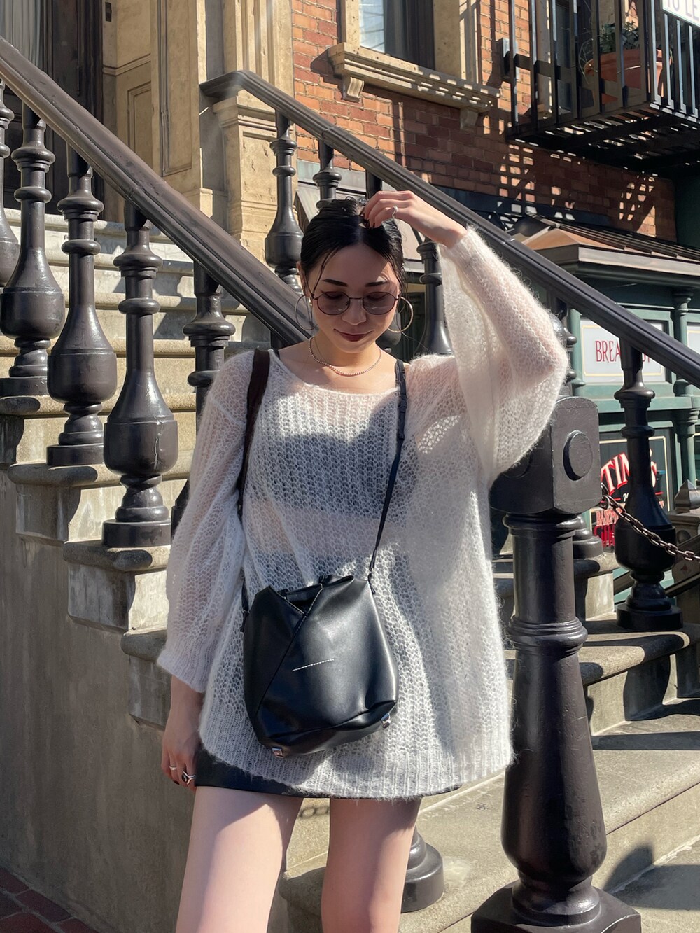 ホワイト系のニット/セーター、ブラック系のショルダーバッグ、グレー系のサングラスを着用したレディースの秋コーディネートの4枚目の写真