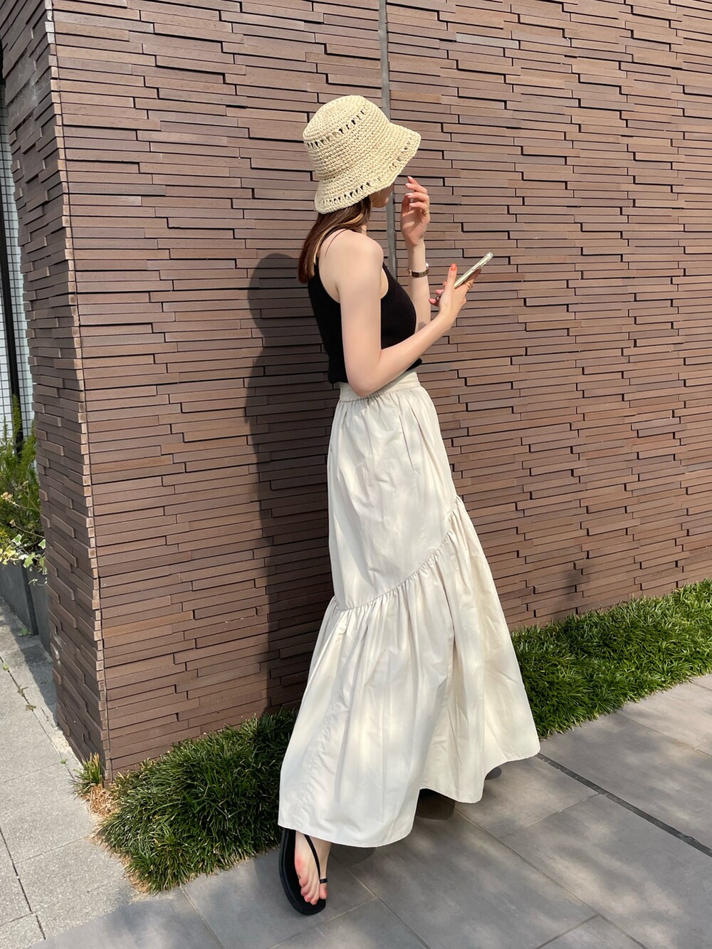 ブラック系のタンクトップ、ホワイト系のスカート、ブラック系のサンダルを着用したレディースの夏コーディネートの2枚目の写真