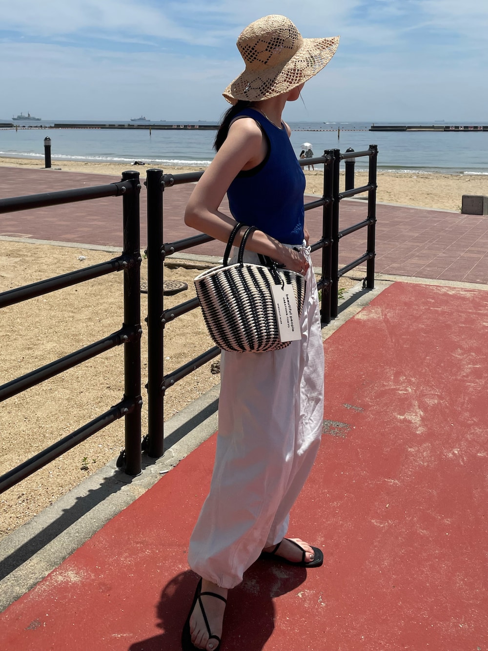 ブルー系のタンクトップ、ブラック系のハンドバッグ、ホワイト系のその他パンツを着用したレディースの夏コーディネートの2枚目の写真