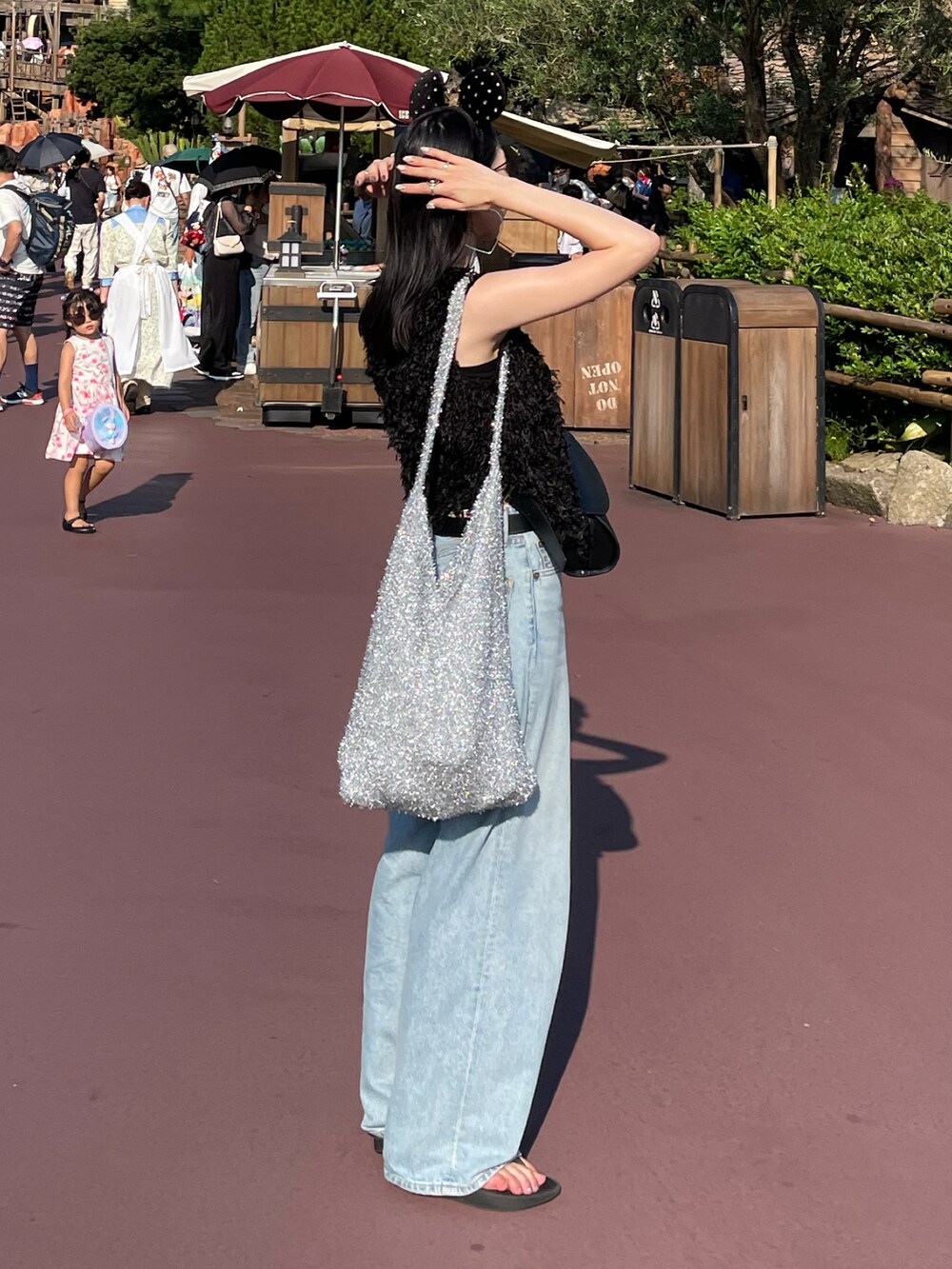 ブルー系のデニムパンツ、ブラック系のサンダル、ブラック系のキャミソールを着用したレディースの夏コーディネートの3枚目の写真