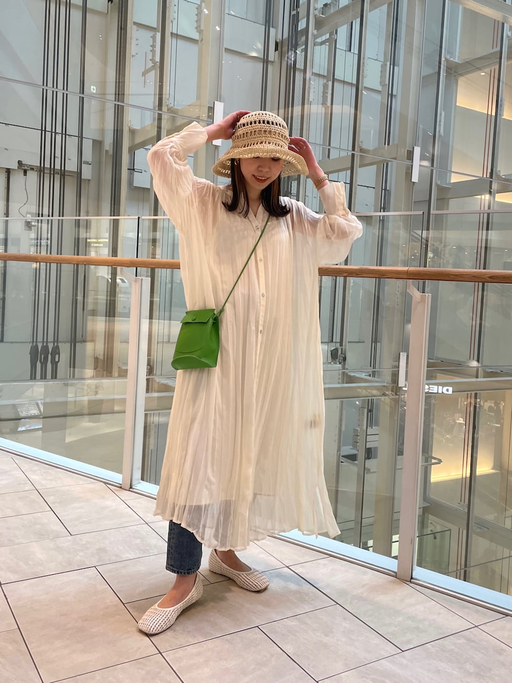 ホワイト系のワンピース、ホワイト系のパンプス、グリーン系のショルダーバッグを着用したレディースの春コーディネートの2枚目の写真