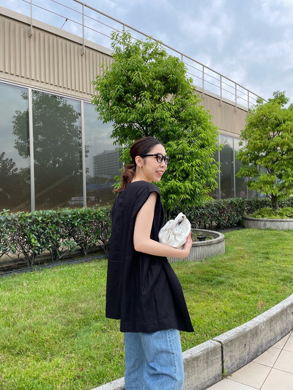 ホワイト系のタンクトップ、ブラック系のベスト、ブルー系のデニムパンツを着用したレディースの夏コーディネートの5枚目の写真