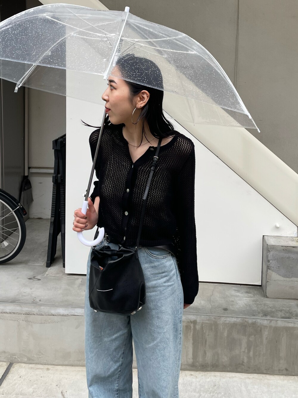 ブルー系のデニムパンツ、ブラック系のカーディガン/ボレロ、ブラック系のショルダーバッグを着用したレディースの春コーディネートの4枚目の写真