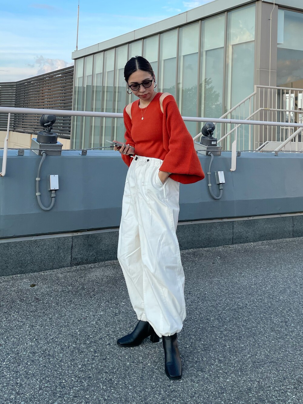 オレンジ系のカーディガン/ボレロ、ホワイト系のその他パンツ、ブラック系のブーツを着用したレディースの秋コーディネートの4枚目の写真