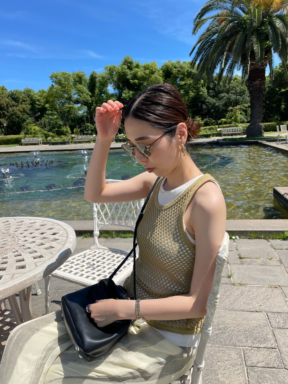 グリーン系のタンクトップ、ブラック系のショルダーバッグ、ベージュ系のその他パンツを着用したレディースの夏コーディネートの5枚目の写真