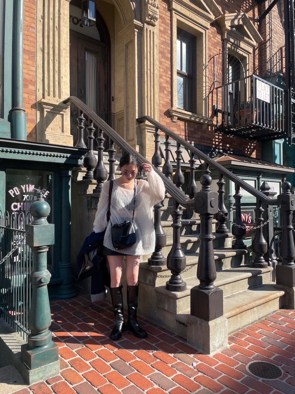 ホワイト系のニット/セーター、ブラック系のショルダーバッグ、グレー系のサングラスを着用したレディースの秋コーディネートの3枚目の写真