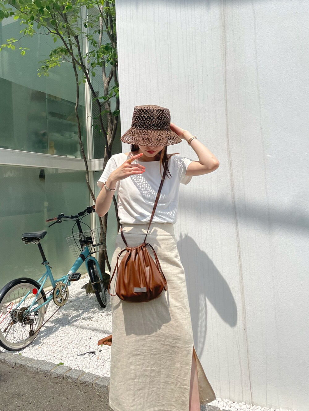 ホワイト系のTシャツ/カットソー、ブラウン系のショルダーバッグ、ブラウン系のサンダルを着用したレディースの夏コーディネートの3枚目の写真