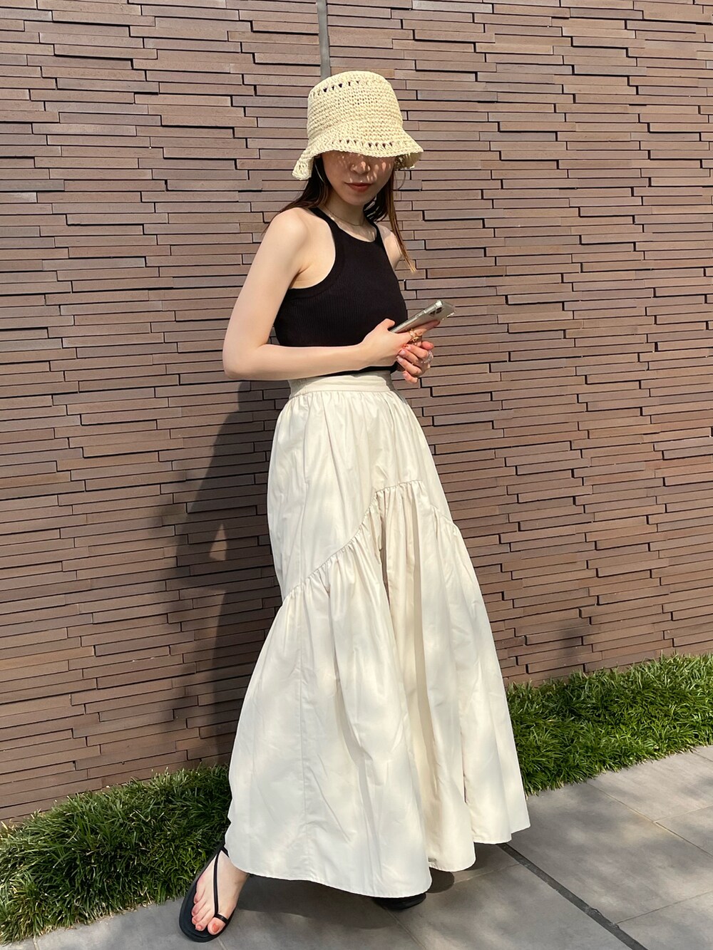 ブラック系のタンクトップ、ホワイト系のスカート、ブラック系のサンダルを着用したレディースの夏コーディネートの4枚目の写真