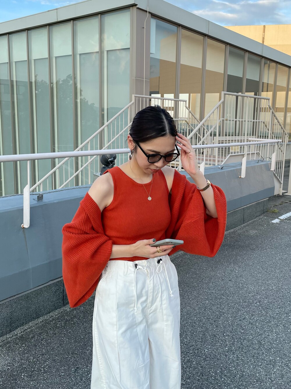 オレンジ系のカーディガン/ボレロ、ホワイト系のその他パンツ、ブラック系のブーツを着用したレディースの秋コーディネートの2枚目の写真