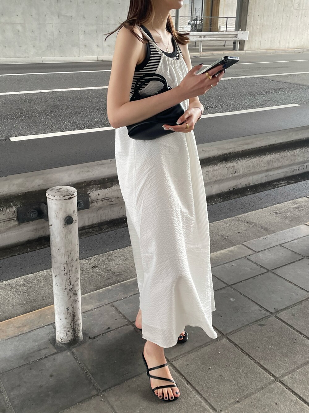 ホワイト系のタンクトップ、ホワイト系のワンピース、ブラック系のハンドバッグを着用したレディースの夏コーディネートの3枚目の写真