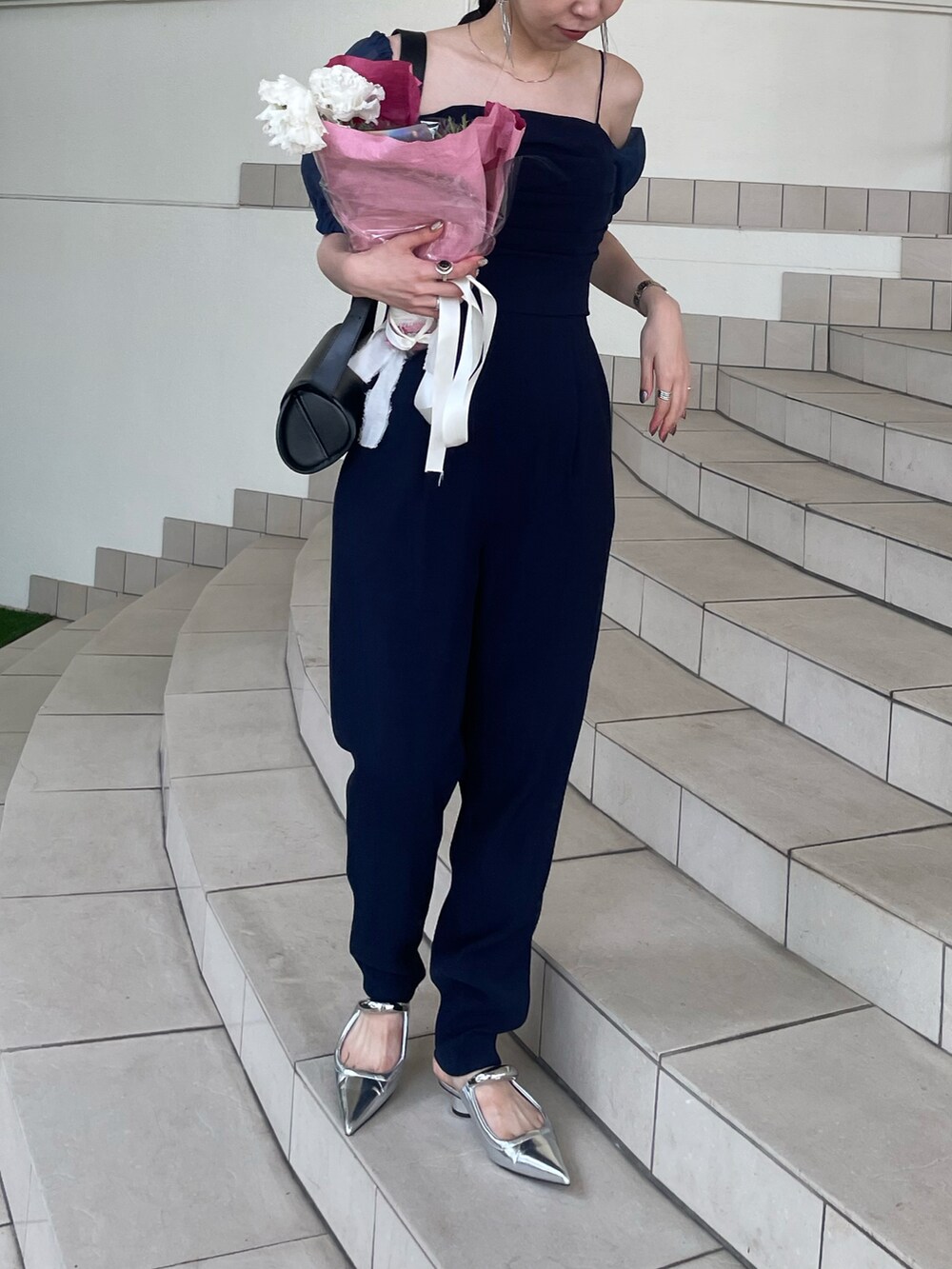 シルバー系のパンプス、ブルー系のドレス、ブラック系のショルダーバッグを着用したレディースの夏コーディネートの3枚目の写真