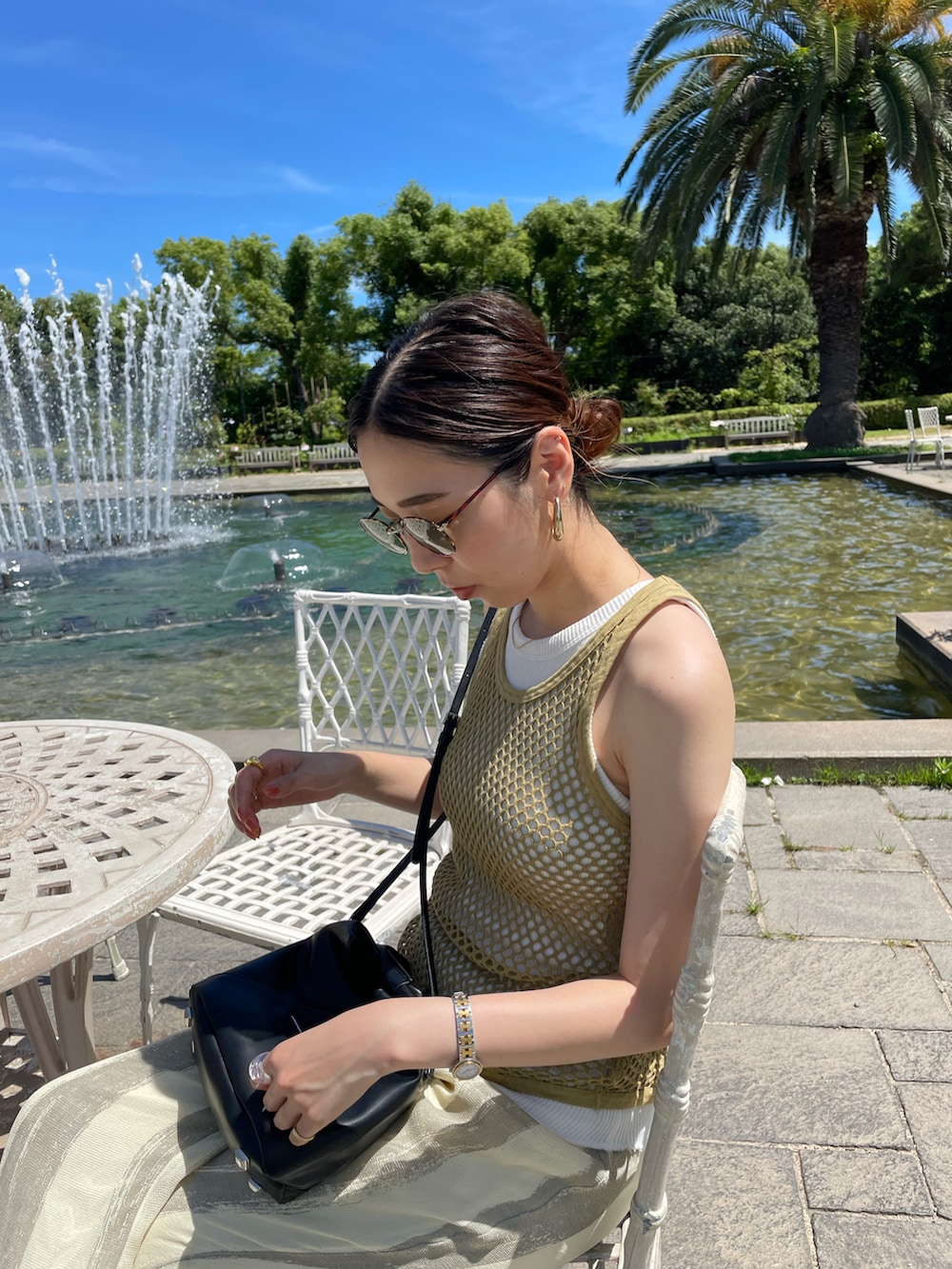 グリーン系のタンクトップ、ブラック系のショルダーバッグ、ベージュ系のその他パンツを着用したレディースの夏コーディネートの2枚目の写真