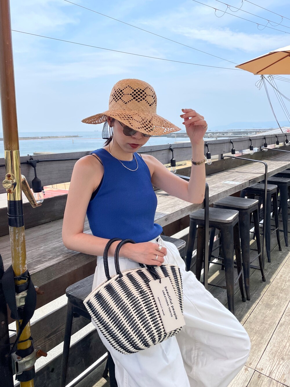 ブルー系のタンクトップ、ブラック系のハンドバッグ、ホワイト系のその他パンツを着用したレディースの夏コーディネートの5枚目の写真