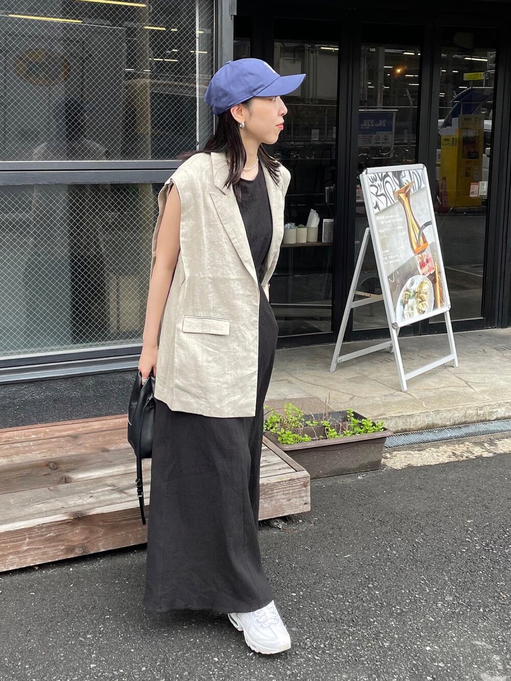 ベージュ系のベスト、ブラック系のショルダーバッグ、ブラック系のワンピースを着用したレディースの春コーディネートの5枚目の写真