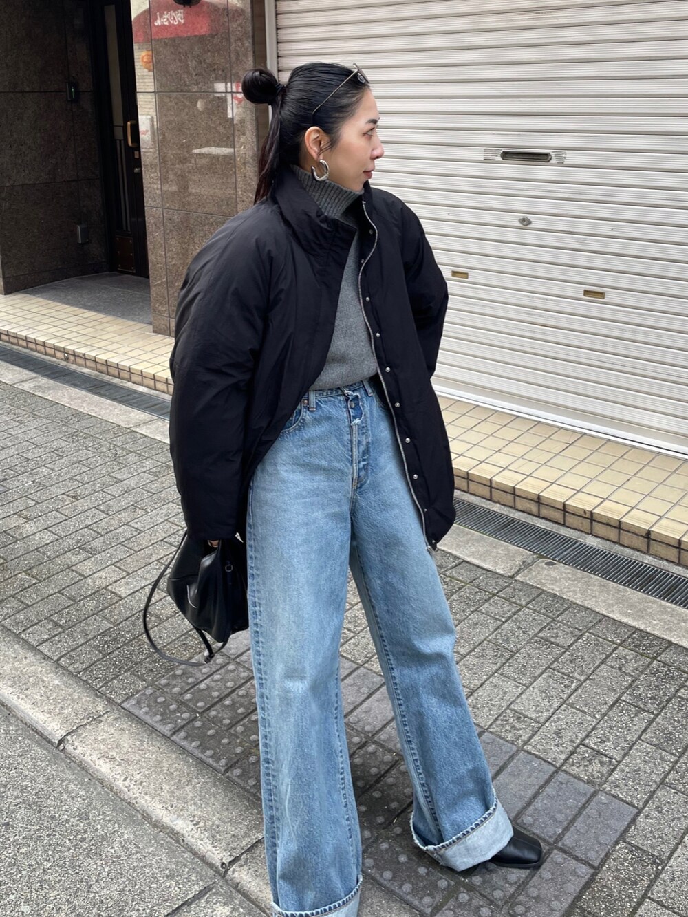 グレー系のニット/セーター、ブラック系のブルゾン、ブルー系のデニムパンツを着用したレディースの冬コーディネートの4枚目の写真