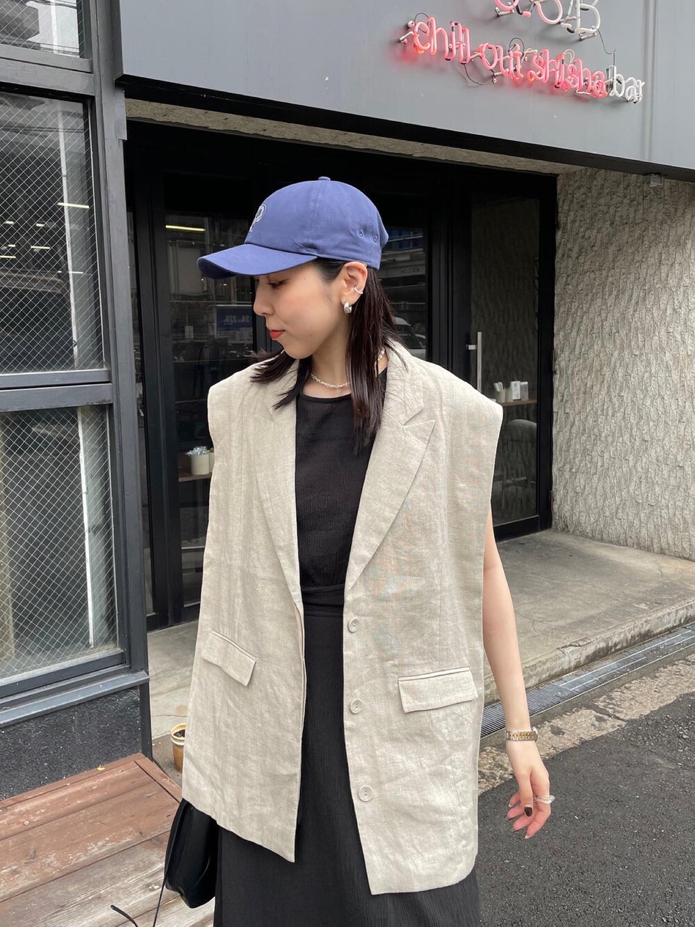 ベージュ系のベスト、ブラック系のショルダーバッグ、ブラック系のワンピースを着用したレディースの春コーディネートの4枚目の写真