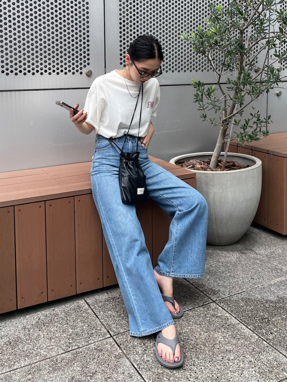 ブルー系のデニムパンツ、ホワイト系のTシャツ/カットソー、グレー系のサンダルを着用したレディースの夏コーディネートの2枚目の写真