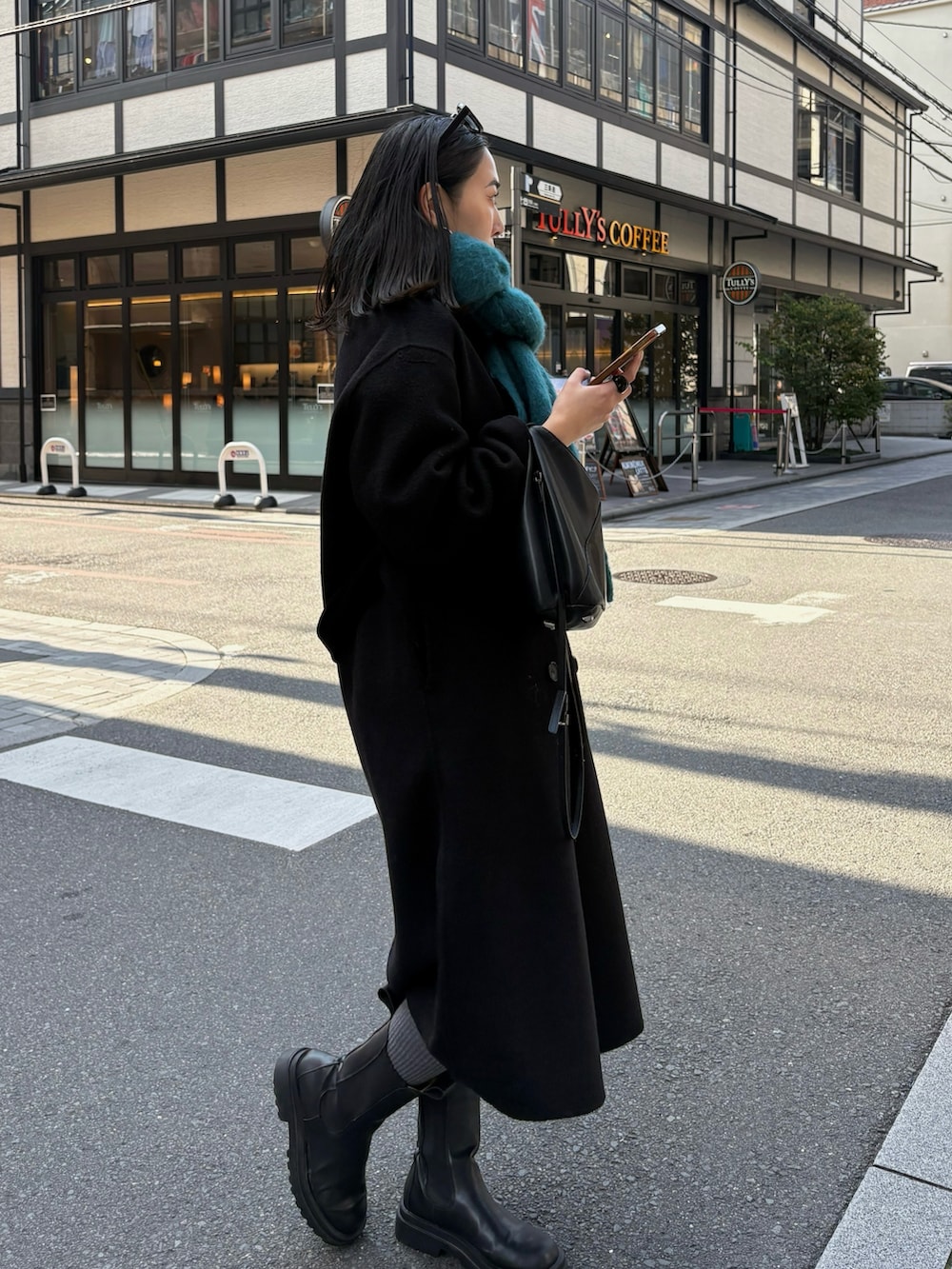 ブラック系のブーツ、ブラック系のショルダーバッグを着用したレディースの秋コーディネートの3枚目の写真