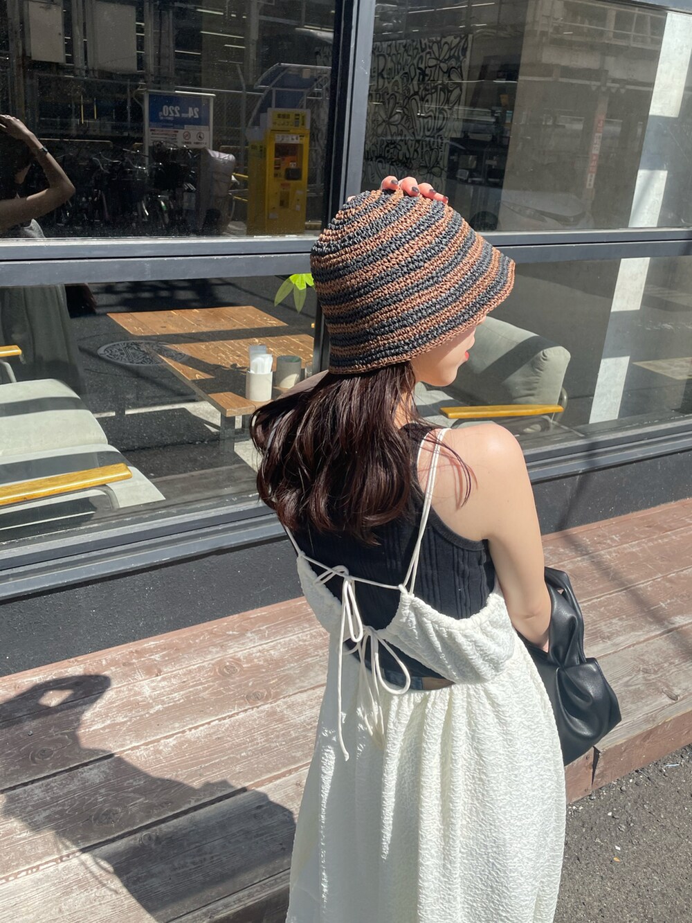 ブラック系のハンドバッグ、ホワイト系のワンピース、ゴールド系のパンプスを着用したレディースの春コーディネートの3枚目の写真