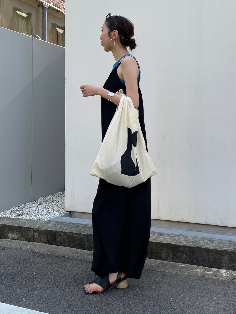 ブラック系のオールインワン・サロペット、ブルー系のタンクトップ、ブラック系のサンダルを着用したレディースの春コーディネートの2枚目の写真