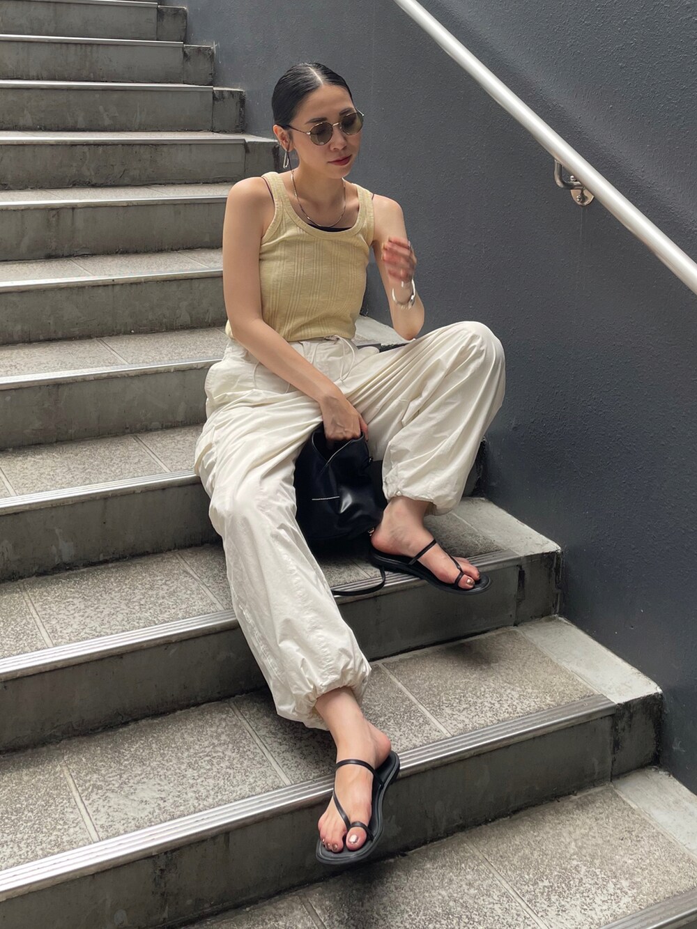 ホワイト系のカーゴパンツ、イエロー系のTシャツ/カットソー、ブラック系のショルダーバッグを着用したレディースの夏コーディネートの2枚目の写真