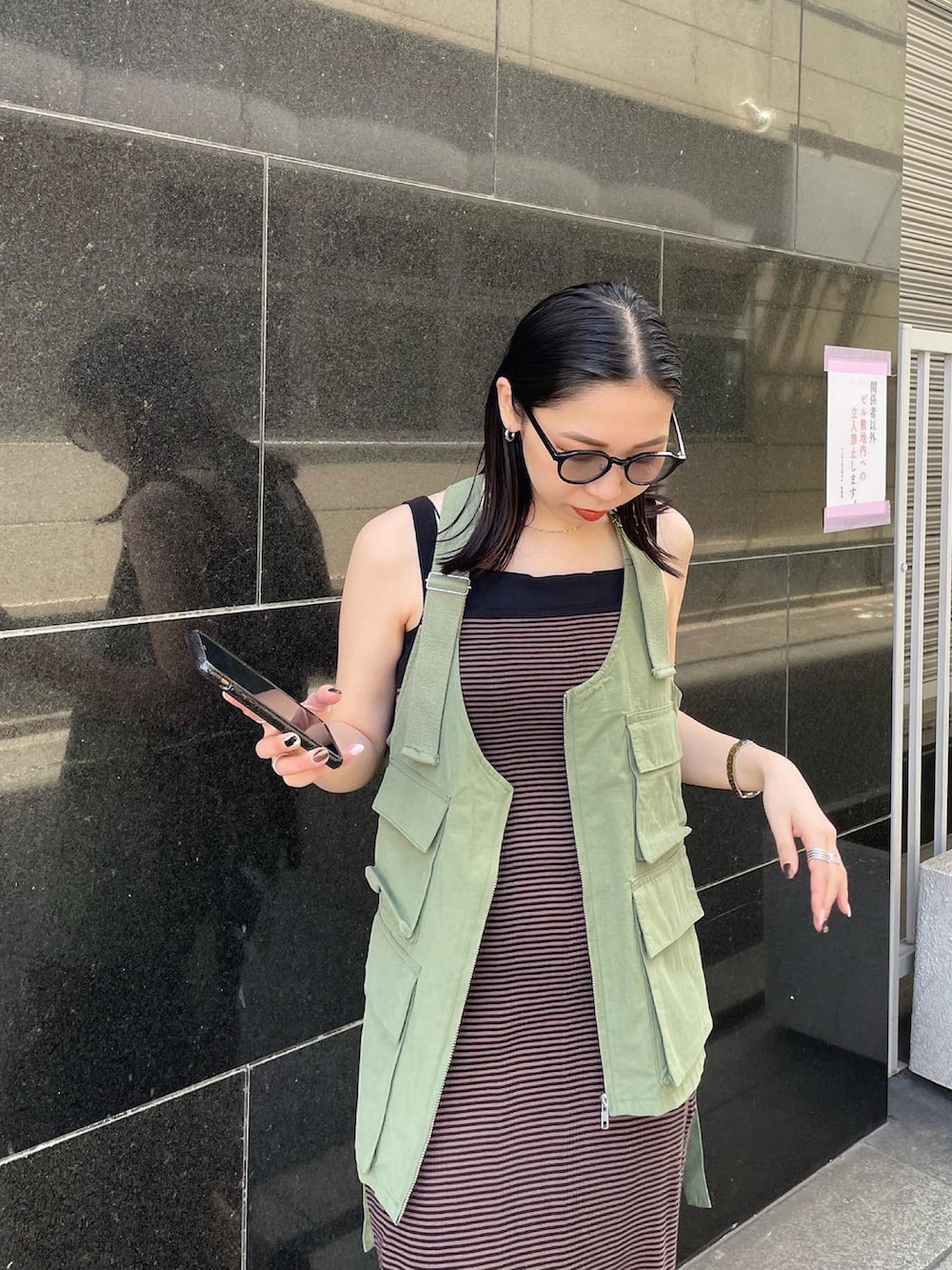 ブラック系のパンプス、ブラウン系のワンピース、グリーン系のベストを着用したレディースの春コーディネートの5枚目の写真