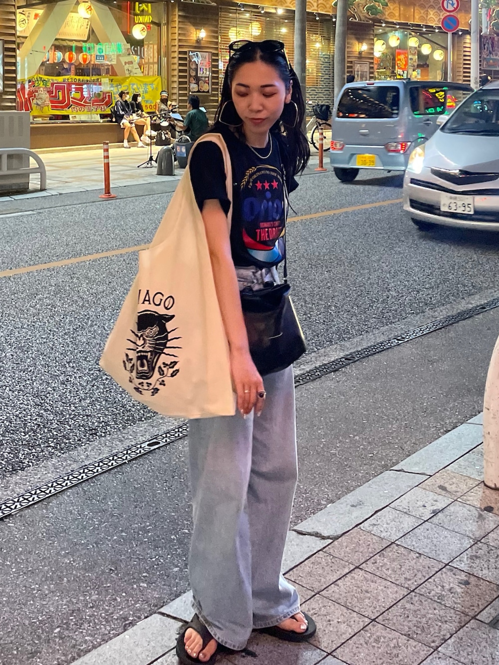 ブルー系のデニムパンツ、ブラック系のショルダーバッグ、ブラック系のサンダルを着用したレディースの秋コーディネートの3枚目の写真