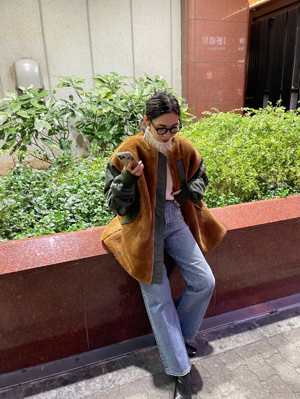 グリーン系のブルゾン、ブルー系のデニムパンツ、ホワイト系のニット/セーターを着用したレディースの秋コーディネートの2枚目の写真