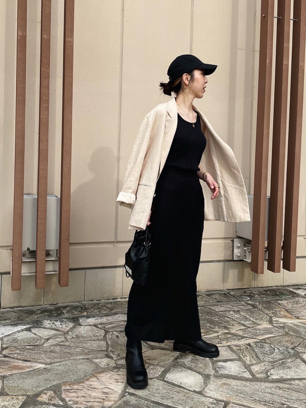 ブラック系のショルダーバッグ、ホワイト系のテーラードジャケット、ブラック系のスカートを着用したレディースの春コーディネートの2枚目の写真