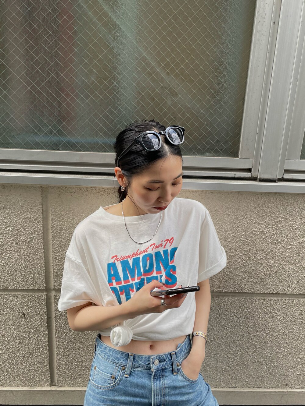 ブルー系のデニムパンツ、ホワイト系のスニーカー、ホワイト系のTシャツ/カットソーを着用したレディースの春コーディネートの4枚目の写真