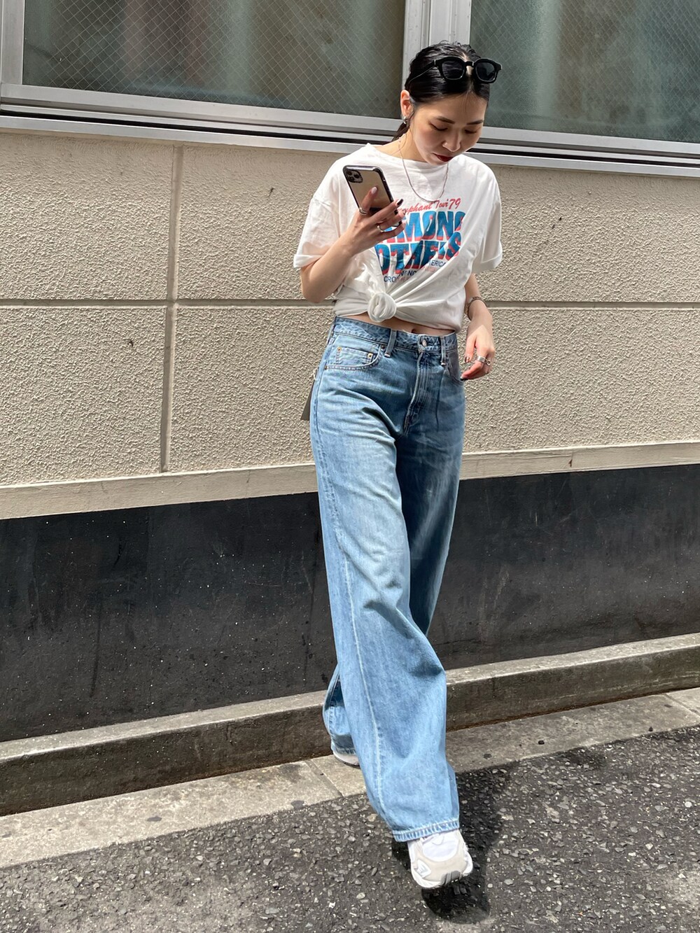 ブルー系のデニムパンツ、ホワイト系のスニーカー、ホワイト系のTシャツ/カットソーを着用したレディースの春コーディネートの3枚目の写真