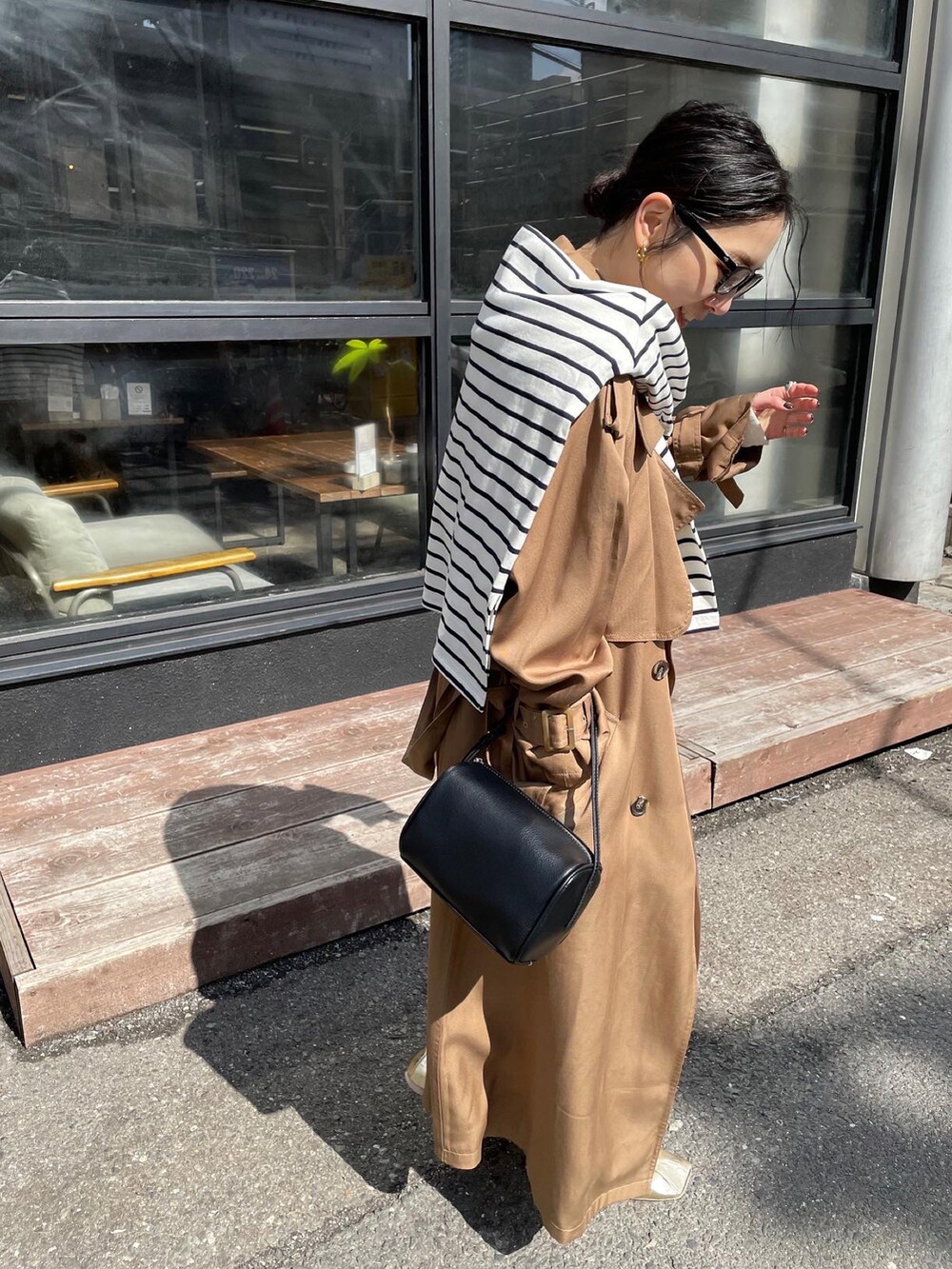 ゴールド系のパンプス、イエロー系のトレンチコート、ホワイト系のワンピースを着用したレディースの冬コーディネートの2枚目の写真