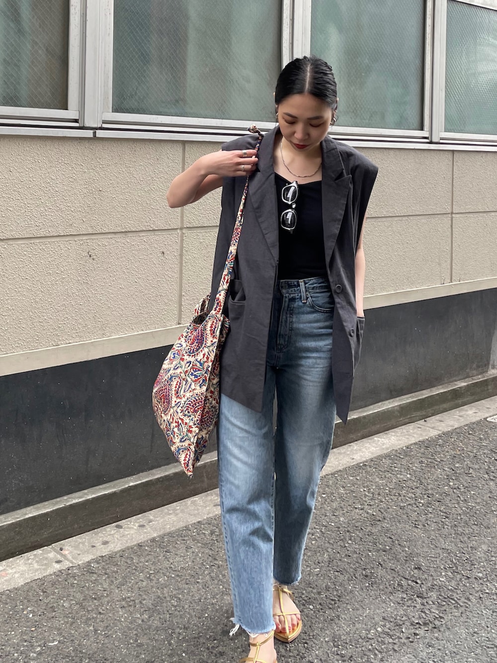 ブルー系のデニムパンツ、ゴールド系のサンダル、ホワイト系のショルダーバッグを着用したレディースの春コーディネートの3枚目の写真