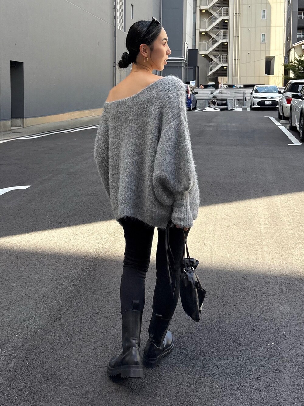 ブラック系のショルダーバッグ、ブラック系のブーツ、ブラック系のデニムパンツを着用したレディースの秋コーディネートの2枚目の写真