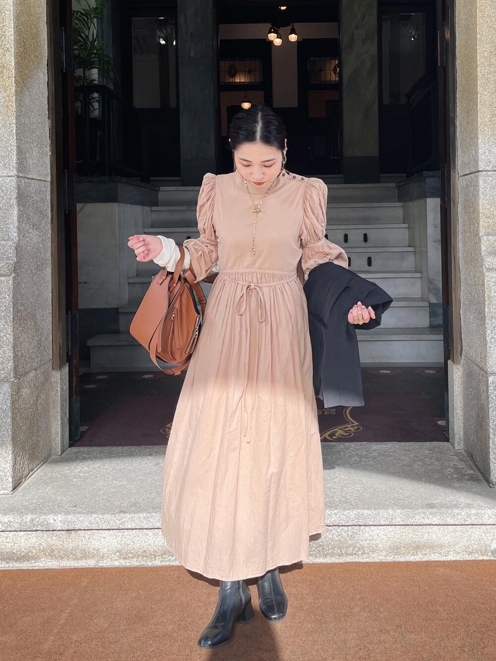 ベージュ系のワンピース、ブラウン系のハンドバッグを着用したレディースの春コーディネートの2枚目の写真