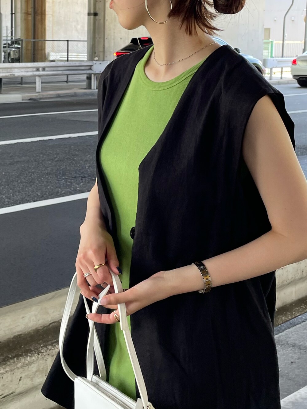 グリーン系のワンピース、ブラック系のベスト、ブラック系のスニーカーを着用したレディースの夏コーディネートの5枚目の写真