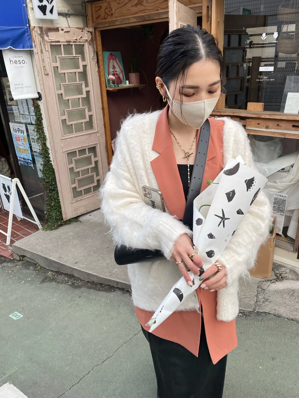 ブラック系のショルダーバッグ、ブラック系のスカート、ホワイト系のカーディガン/ボレロを着用したレディースの冬コーディネートの3枚目の写真