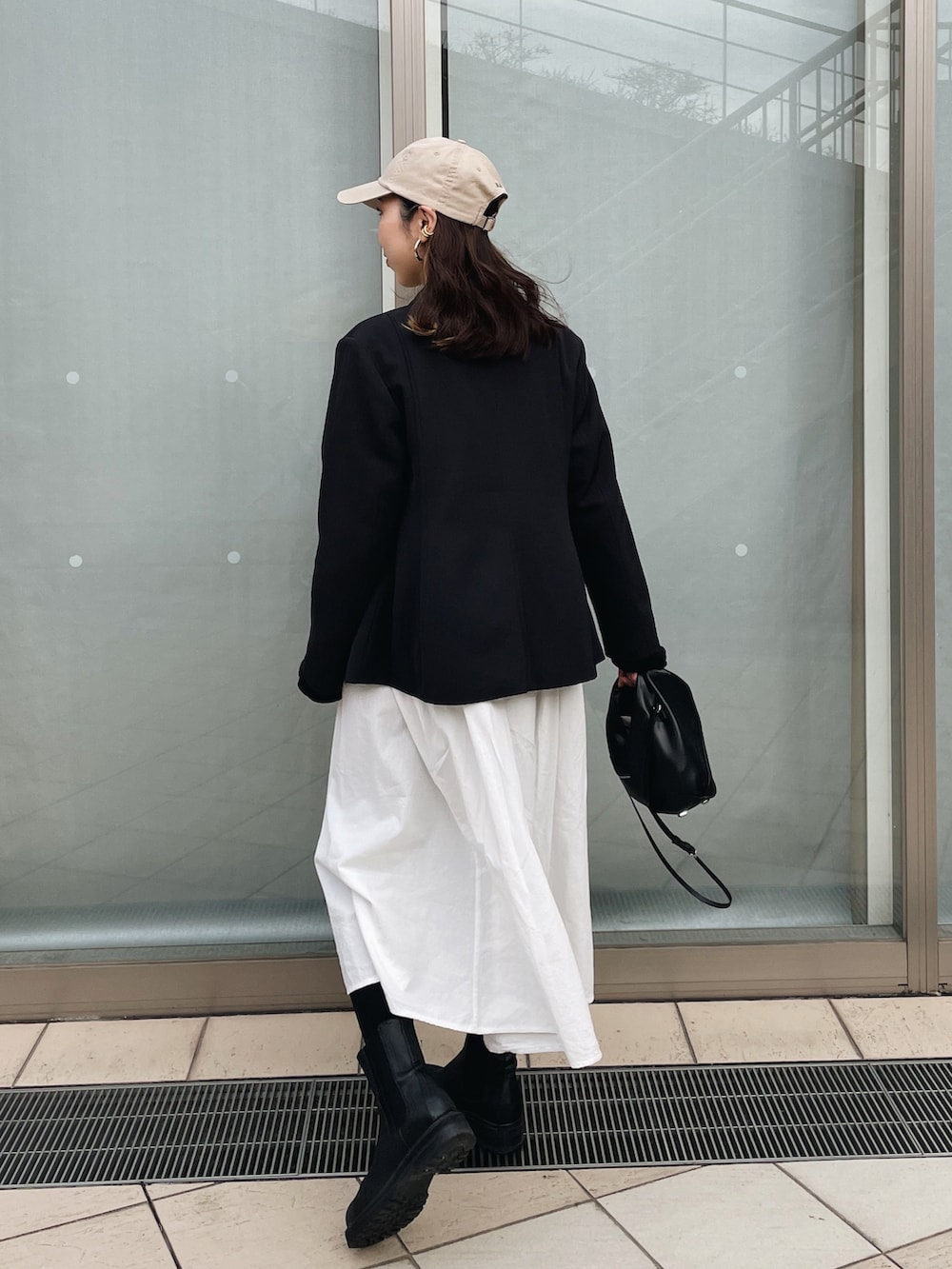 ブラック系のテーラードジャケット、ブラック系のショルダーバッグ、ブラック系のブーツを着用したレディースの春コーディネートの4枚目の写真