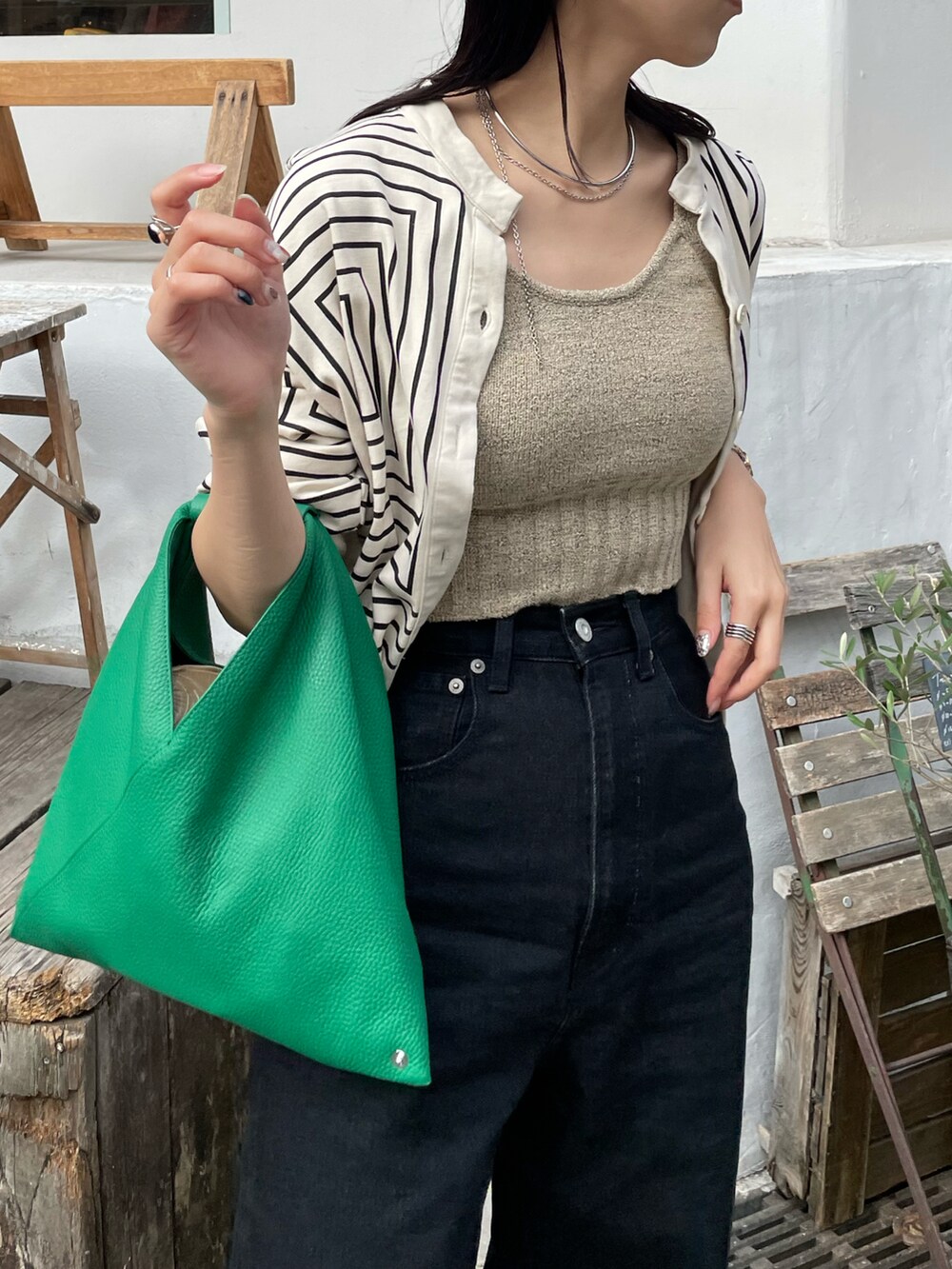 ブラック系のデニムパンツ、グリーン系のショルダーバッグ、ゴールド系のパンプスを着用したレディースの秋コーディネートの4枚目の写真