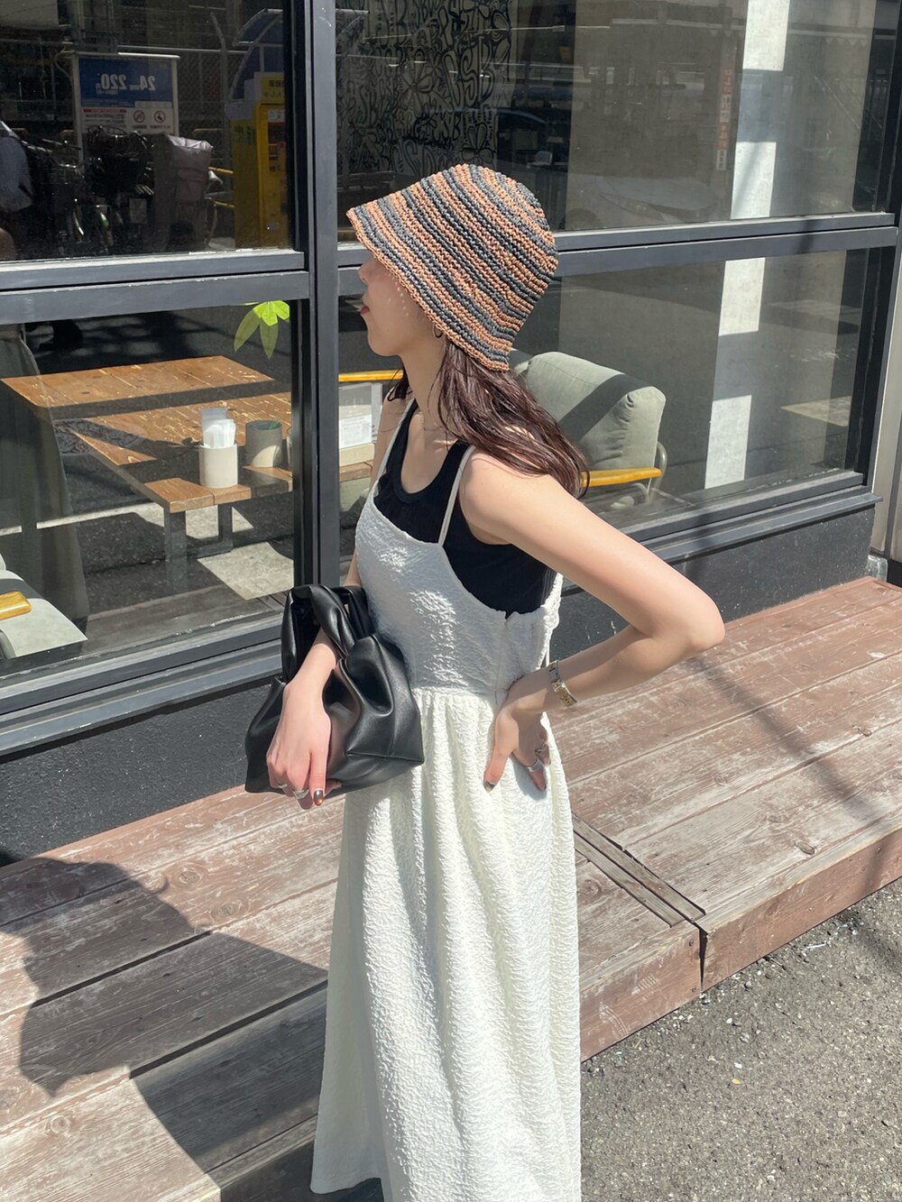 ブラック系のハンドバッグ、ホワイト系のワンピース、ゴールド系のパンプスを着用したレディースの春コーディネートの4枚目の写真