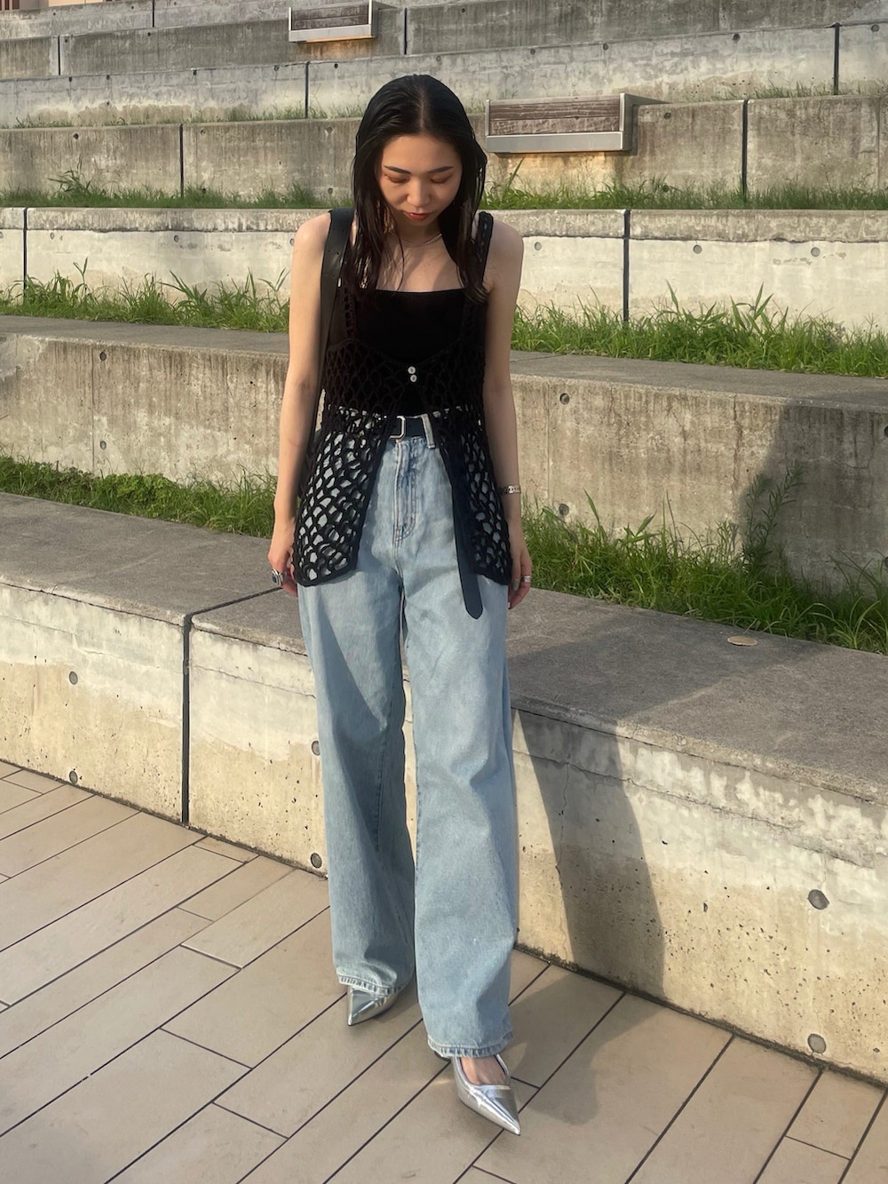 ブルー系のデニムパンツ、ブラック系のショルダーバッグ、ブラック系のキャミソールを着用したレディースの夏コーディネートの2枚目の写真