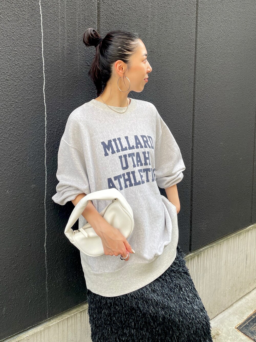 ブラック系のスカート、グレー系のスウェット、ブラック系のスニーカーを着用したレディースの秋コーディネートの3枚目の写真