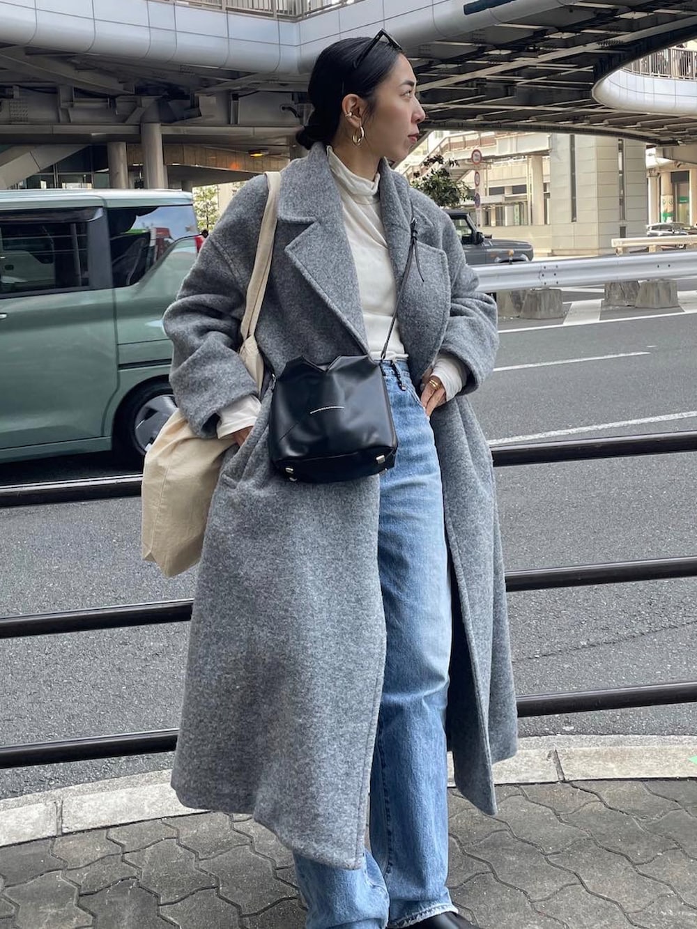 ブラック系のブーツ、ブルー系のデニムパンツ、ブラック系のショルダーバッグを着用したレディースの冬コーディネートの2枚目の写真