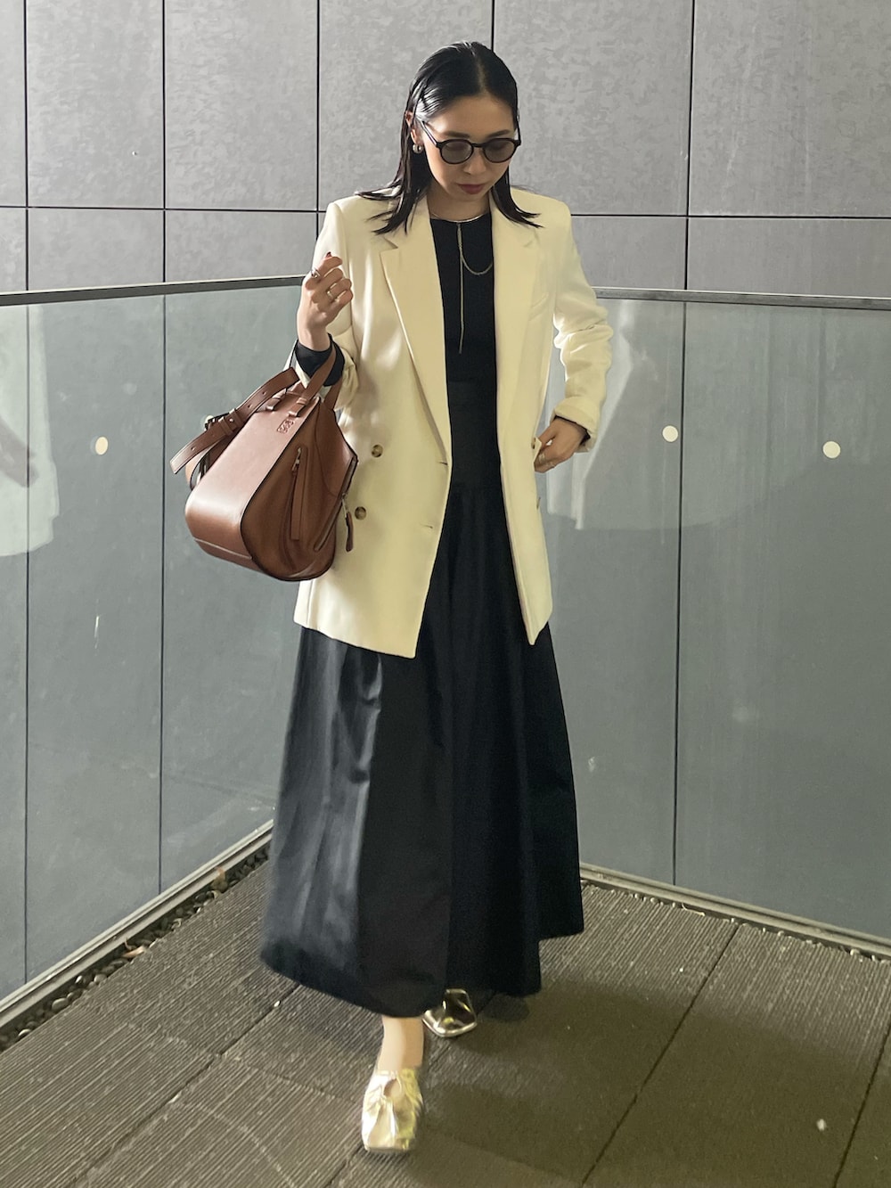 ブラウン系のバックパック/リュック、ゴールド系のパンプス、ブラック系のTシャツ/カットソーを着用したレディースの春コーディネートの2枚目の写真