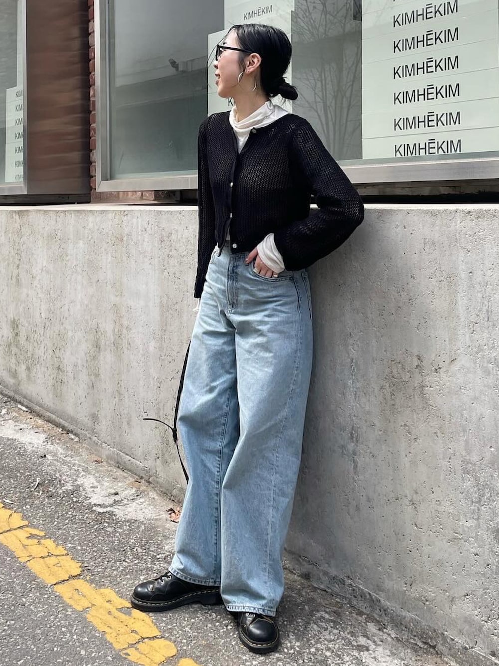 ブルー系のデニムパンツ、ブラック系のカーディガン/ボレロ、ブラック系のショルダーバッグを着用したレディースの春コーディネートの3枚目の写真