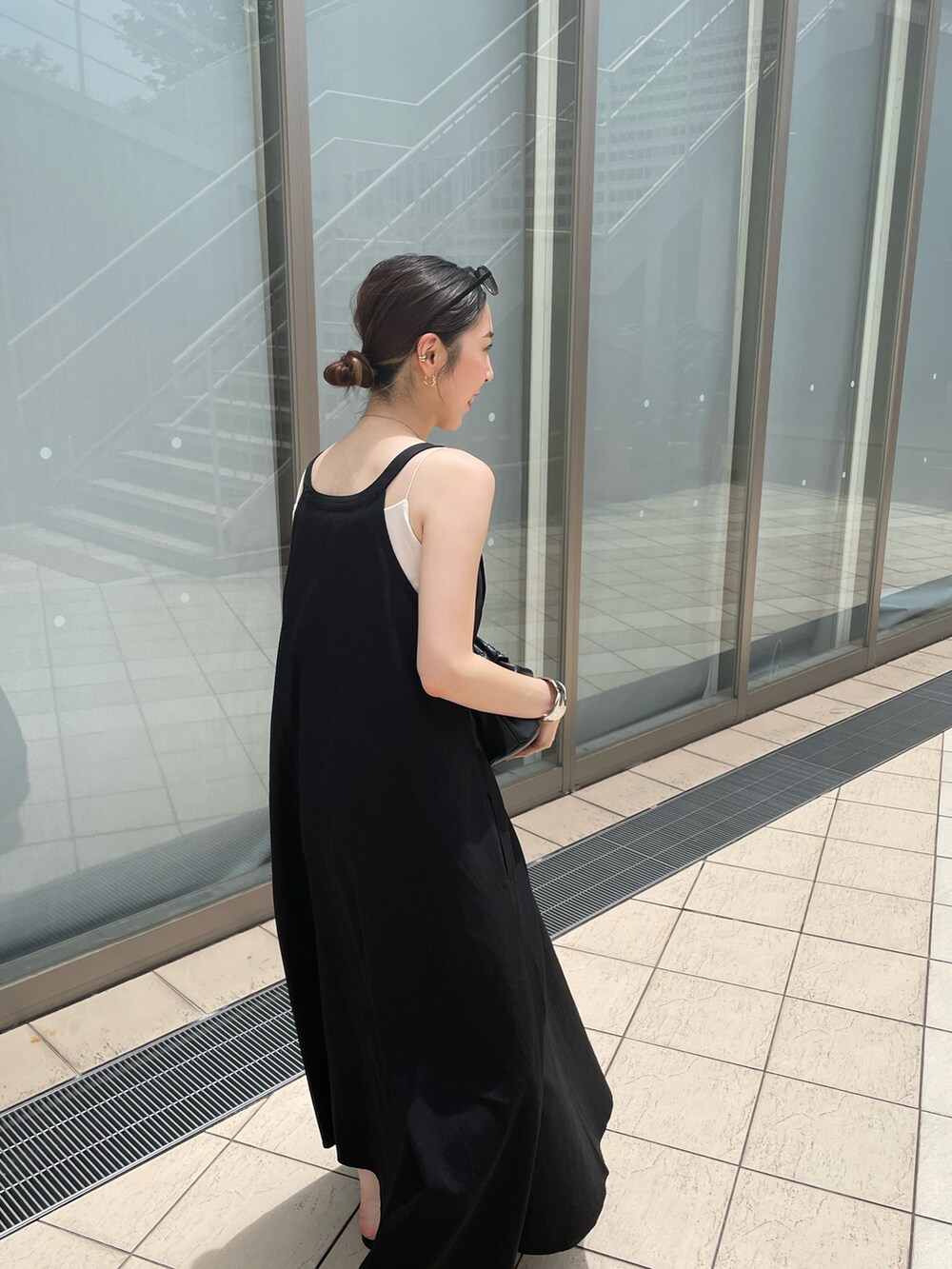 ブラック系のハンドバッグ、ブラック系のワンピース、ブラック系のサンダルを着用したレディースの夏コーディネートの3枚目の写真