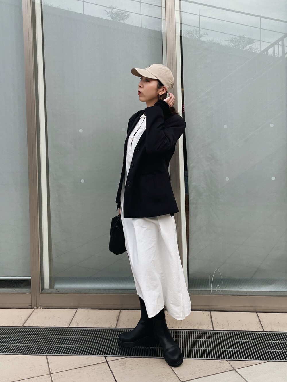 ブラック系のテーラードジャケット、ブラック系のショルダーバッグ、ブラック系のブーツを着用したレディースの春コーディネートの2枚目の写真