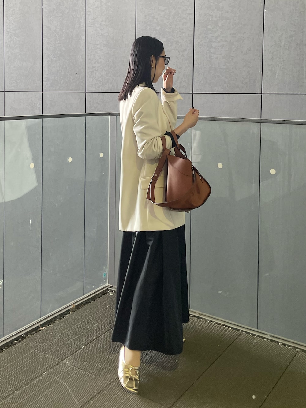 ブラウン系のバックパック/リュック、ゴールド系のパンプス、ブラック系のTシャツ/カットソーを着用したレディースの春コーディネートの3枚目の写真