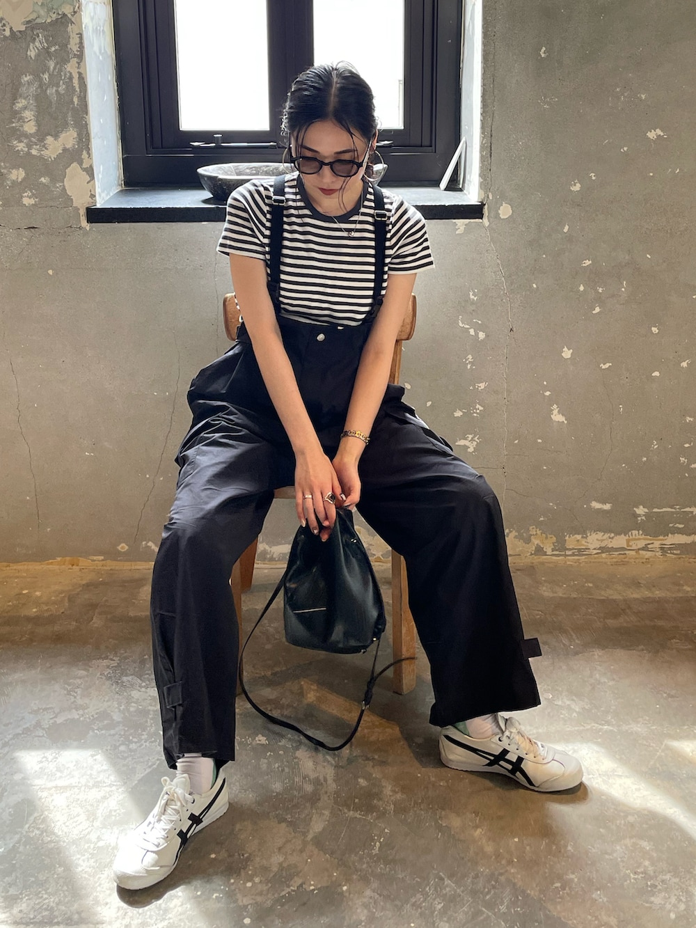 ブラック系のサロペット/オーバーオール、グレー系のTシャツ/カットソー、ホワイト系のスニーカーを着用したレディースの春コーディネートの3枚目の写真