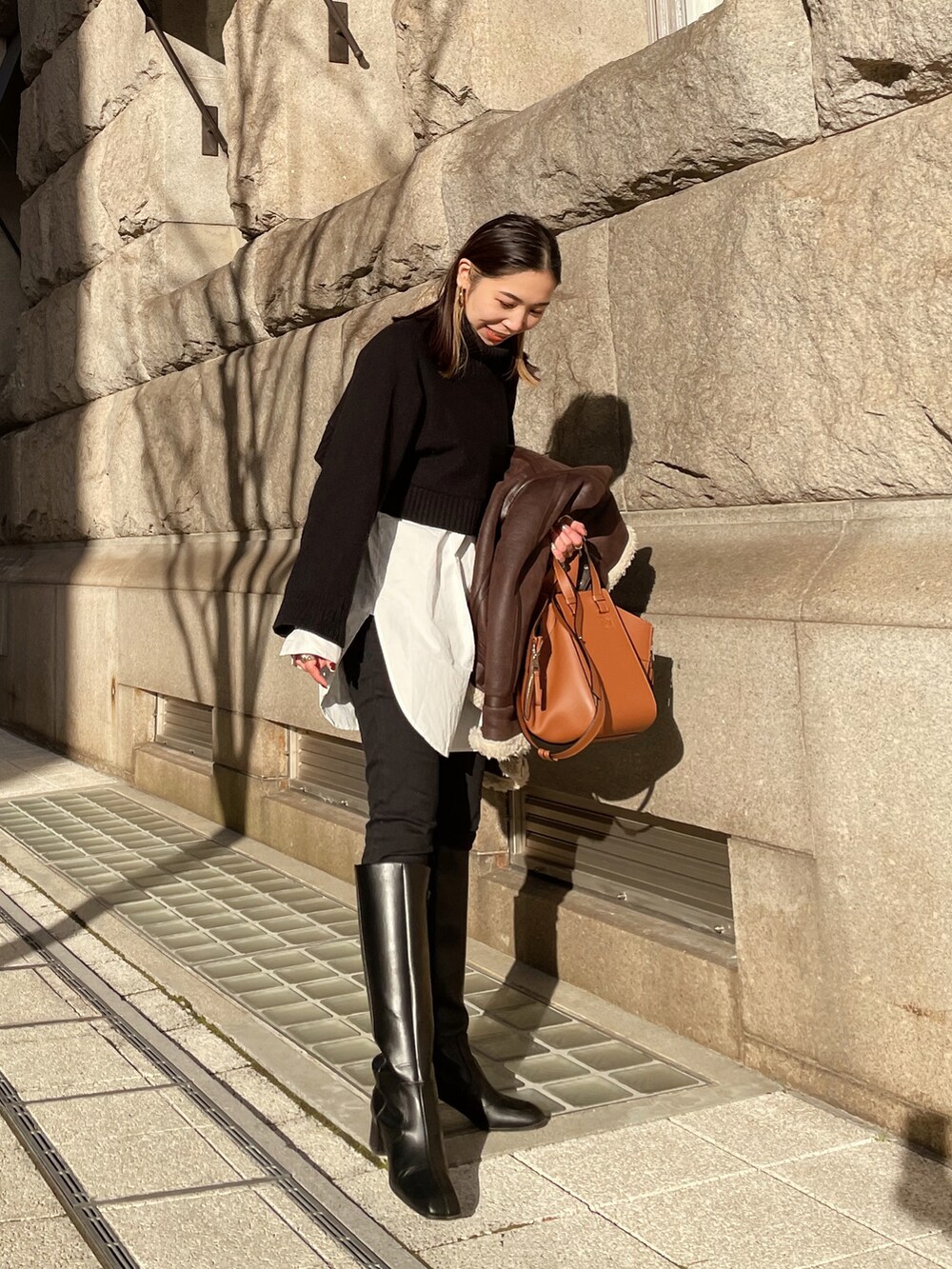 ブラック系のブーツ、ホワイト系のシャツ/ブラウス、ブラック系のニット/セーターを着用したレディースの冬コーディネートの2枚目の写真